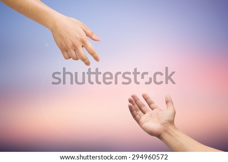 Human\'s hands help together on blurred twilight sky backgrounds.helping hands concept. blurred twilight backgrounds in pastel tone.