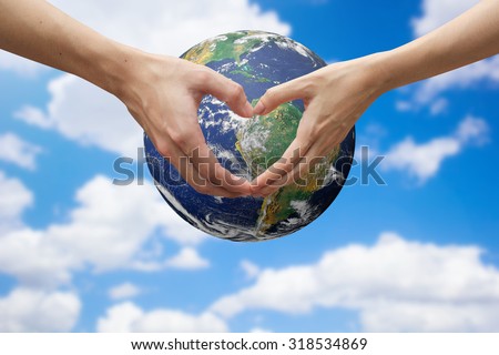 close up male and female hands making heart shape over the world on blur sky.safe the world concept :symbols of human\'s hands to show that they love the world.Elements of this image furnished by NASA