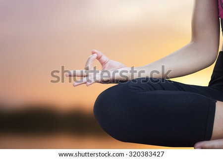 close up and selective focus on fingers of asian woman in yoga over blurred sunset backgrounds : asian woman in yoga pattern exercise for healthy life :concentrate woman yoga concept.
