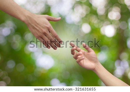 helping hand and hands praying on blurred green nature background : hand praying and hand blessing for helping each other:helping hand concept.family and friends concept.