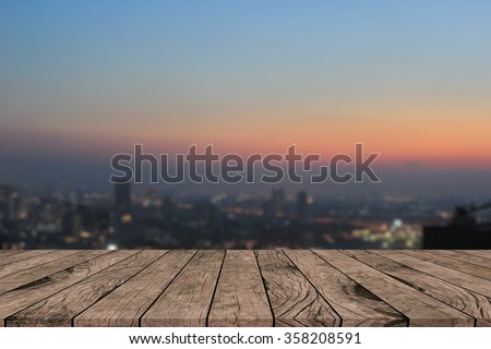 Blurred dark night city background with wood panels perspective.blur downtown skyline backdrop concept.blurry urban sunset/sunrise hours wallpaper with wood tiles stripe floorboard for montage display