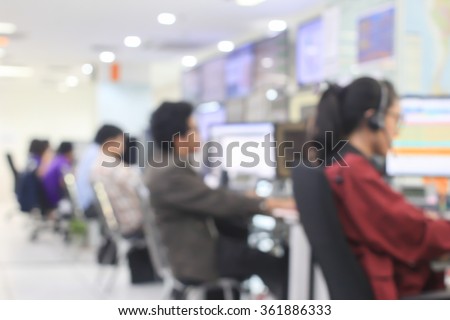 blurred woman/man operator working or searching on computer at office room:blur of woman monitoring and talking on headphone concept:blurry of people,business,technology :call centre help desk concept