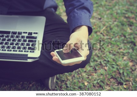 close up on business man work on smartphone and laptop at outdoor:man use electronics mobile notebook device equipment:people city lifestyle and technology concept.vintage tone retro film effect image