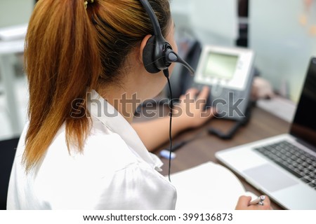 close up call center woman working in office room:focus on headphone of asian girl response answer customer question or partner concept:people technology innovation:service support business:operation