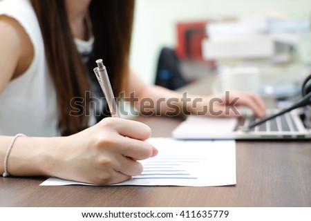 close up work woman writing on paper and typing on laptop computer in office room,student girl doing homework or lecture lesson or researching about project:busy people:business and education concept