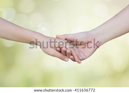 support and assistance human hands on blurred glow green bokeh nature background:helping hand concept.close up soul mate handshake touching together:love affection:better life and take care:nursing