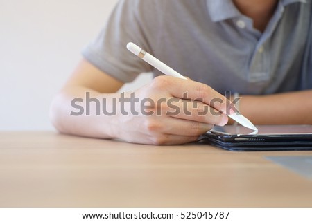 close up student holding smart pen writing and drawing on tablet touch screen devices:education business technology concept.