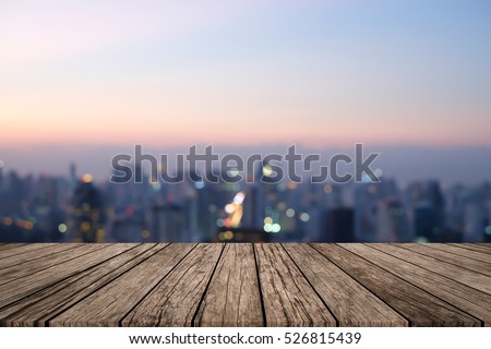 Blurred dark night city background with wood panels perspective.blur downtown skyline backdrop concept.blurry urban sunset/sunrise hours wallpaper with wood tiles stripe floorboard for montage display