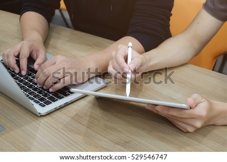 close up soft focus on man hand typing on keyboard laptop and working collaborate with colleagues who using tablet for explain about assignment job.