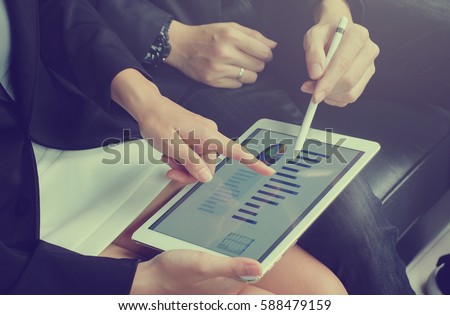 close up business woman hand finger point on screen display tablet for explain detail statistic graph with business man holding stylus pen for teaching.