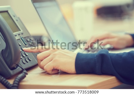 close up man hand point to press button number on telephone office desk.hotline employee concept