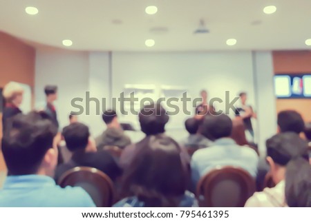 abstract blurred group of people listening speaker motivate for power up of working in convention hall , meeting business concept