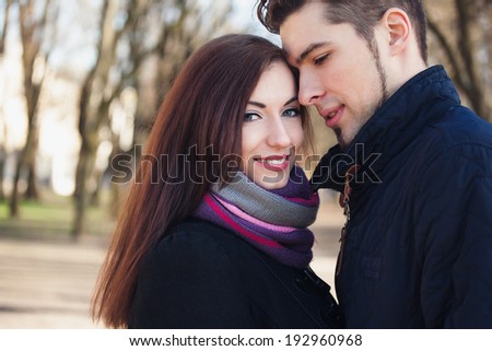 Young beautiful couple, man is leaning to woman. Woman is looking in camera and smiles.