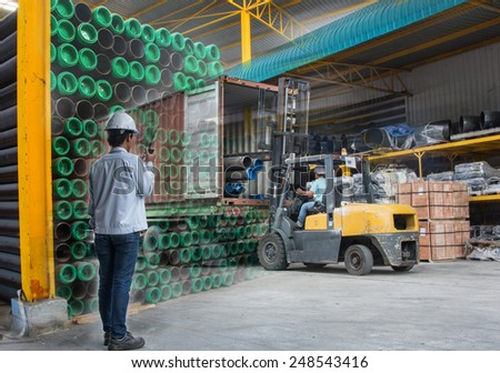 Double exposure of warehouse laborer team at unloading works with forklift loader and Steel pipes storage