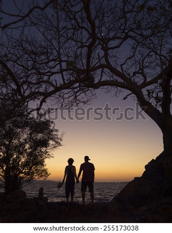 silhouette loving couple holding hands at beach during sunset