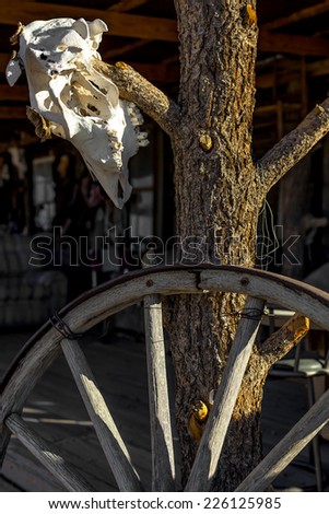 A wagon wheel and a cattle skull adorn a porch.