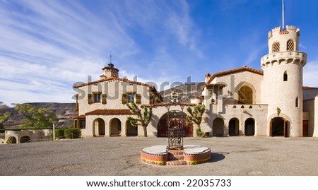 Spanish Villa in Death Valley. Wrought iron ornament and ceramic tiles on fountain. Wooden gate, towers. Spanish architecture with ceramic roof tiles. Blue sky with stratus clouds. Scotty\'s Castle.