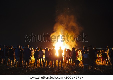 LAREDO, SPAIN - JUNE 24, 2014: People celebrate St John\'s Eve around a bonfire in a beach in northern Spain. St John\'s eve celebration around a bonfire is reminiscent of Midsummer\'s pagan rituals.