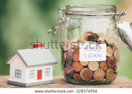 Loan money in a jar and a miniature house on a table