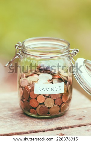 Open jar full of coins with the word saving on a label.