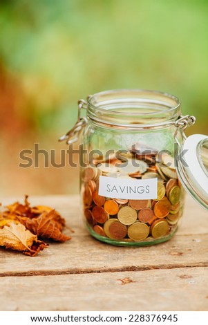 Money jar full of coins with a savings label on it.