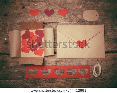 Red heart shapes, envelopes and a tag on a table ready to create a Valentine\'s day card