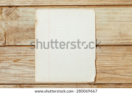 A blank old piece of paper on a wooden desktop.