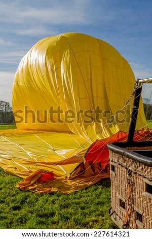 A yellow hot air balloon is being prepared for transportation after landing.