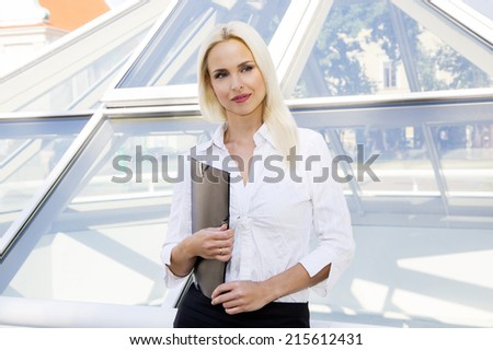 Portrait of a business woman in white on a background of a glass window. with a folder in hands