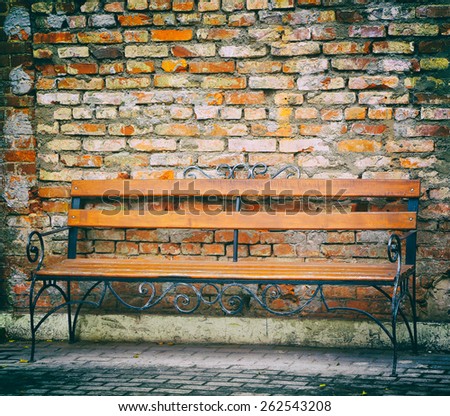 old metal bench on a background of an old brick wall,  photo in old image style.