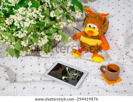 morning. jasmine flowers in a basket on the bed. Toys bee, coffee cup, notebook. background white curtains.