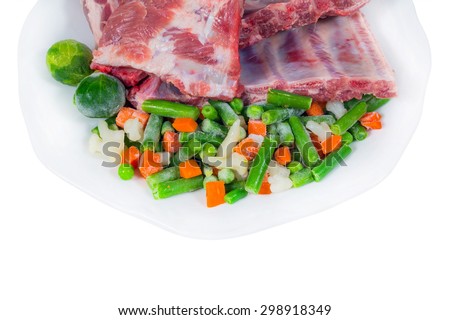 raw meat and frozen vegetables on a plate. cooking delicacies. White background. isolated. fragment