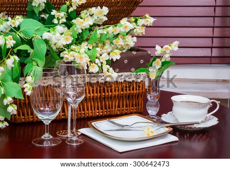 dinner set, coffee mug and jasmine flowers on a background of wicker baskets. interior, wooden table.