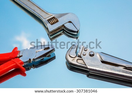 metal tools pliers, wrench, adjustable wrench on the background of the mirror, the reflection of the sky. fragment