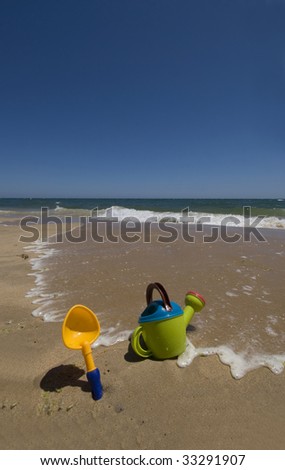 Childs sand bucket and toys on scenic sunny beach with waves