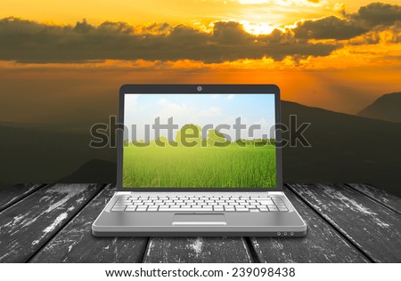 laptop notebook on the wood  table with sun ray and sky background