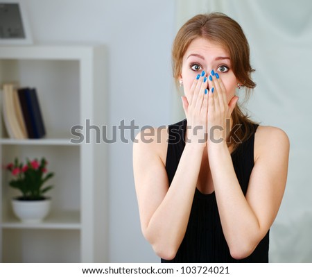 Portrait of young shocked girl holding her face