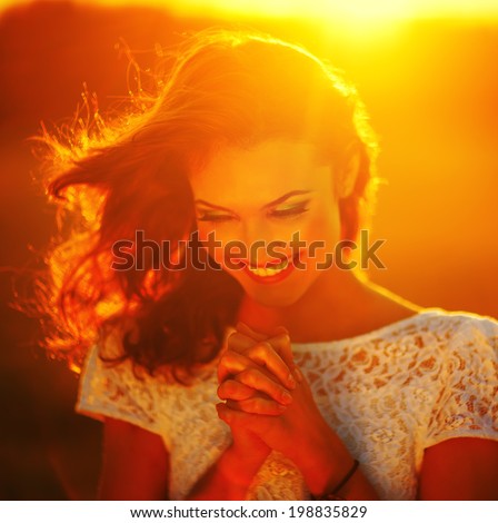 A young girl prays at sunset rays