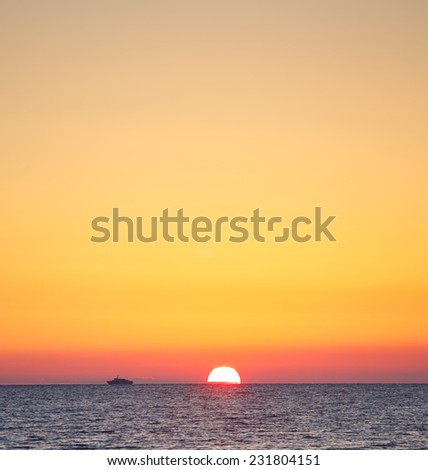 Beautiful sunset above the sea with the ship on the horizon