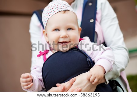 little cute girl in sling. Mother`s hand hold her. Summer time