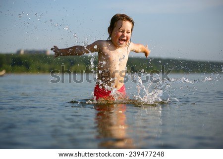 Little girl laughing and crying in the spray of waves at sea on a sunny day