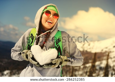 Winter sport, snowboarding - portrait of young snowboarder girl With snow heart in hands