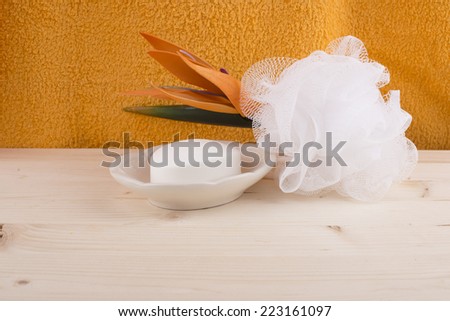Soap-dish with soap,wisp of bast,orange flower on the wooden table