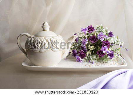 Teapot, tray and violet flowers on the beige organza