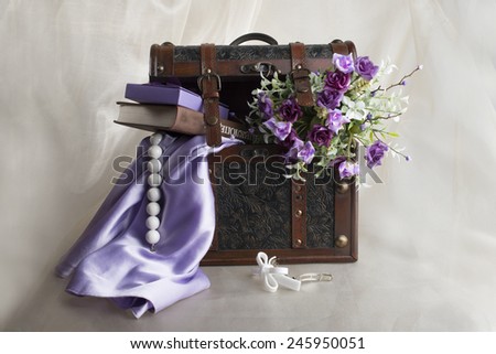 Brown casket on the beige background , violet flowers, book, barrette and bead