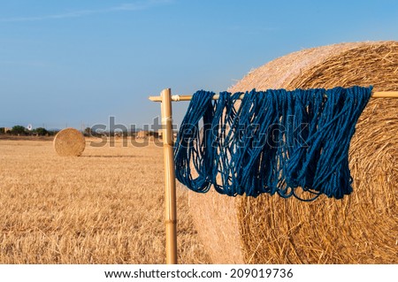blue wool drying in the sun in a meadow with straw rolls