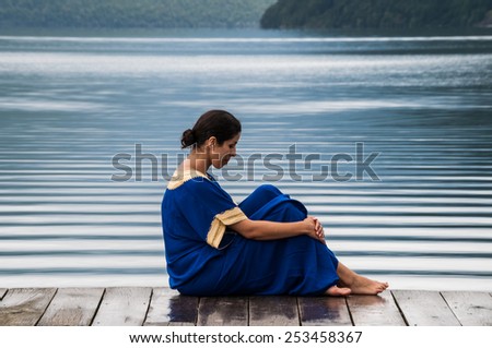woman sitting on a pier at Lake Nelson in New Zealand