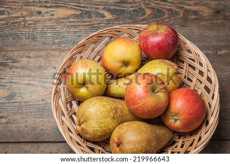 Pumpkins, apples, pears, tomatoes and basket on a wooden plate.