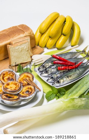 Kitchen counter with bread, portuguese pies, bananas, french garlic and mackerel fish.