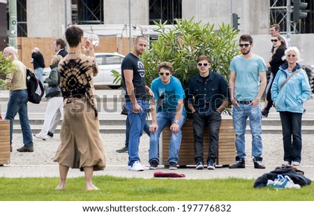 BERLIN, GERMANY - MAY 30, 2014:Performance of street artist on the Unter den Linden.Young tourists in sunglasses watching the show. Berlin is filled with street performers during summer.